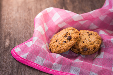 Chocolate chip cookies with pink cloth on wooden table.