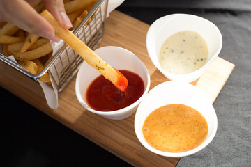 French fries in a metal basket with sauce on a wooden floor.