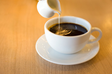 Pouring condensed milk into the coffee.
