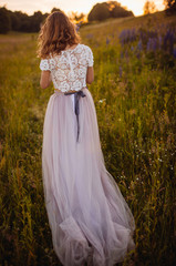 Woman in marvelous dress walks on the field with flowers