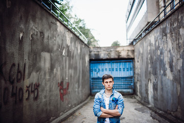 Lonely young man dressed in casual style stands on the street