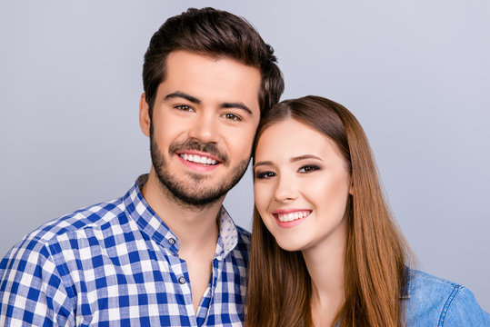 Family portrait. Two young cute lovers are looking at the camera and smile, wearing casual outfits, bonding on the pure background