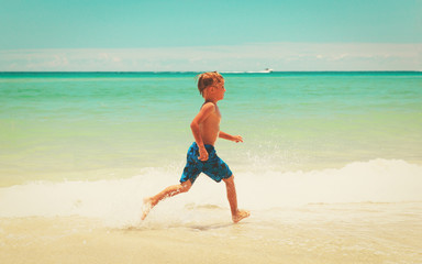 Fototapeta premium little boy run play with waves on beach