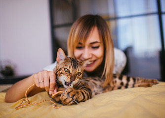 Woman plays with a rope with Bengal cat