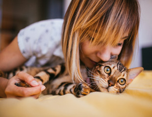 Woman and Bengal cat lie on the bed