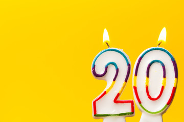 Number 20 birthday celebration candle against a bright yellow background