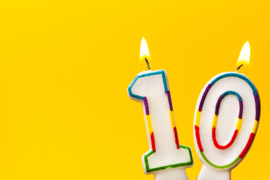 Number 10 birthday celebration candle against a bright yellow background
