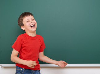 Schoolboy play and laugh near a blackboard, empty space, education concept