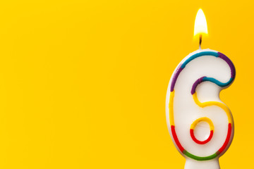 Number 6 birthday celebration candle against a bright yellow background - obrazy, fototapety, plakaty