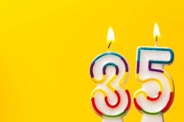Number 35 birthday celebration candle against a bright yellow background