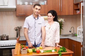 couple cooking in kitchen interior with fresh fruits and vegetables, healthy food concept, pregnant woman and man