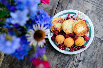 A still-life of flowers, raspberries and baking.
