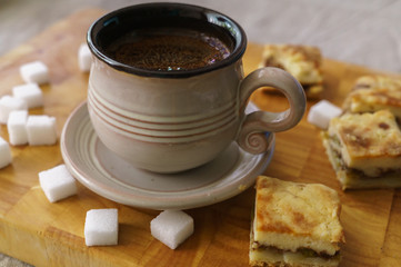 A cup of fresh coffee with pieces of cake.