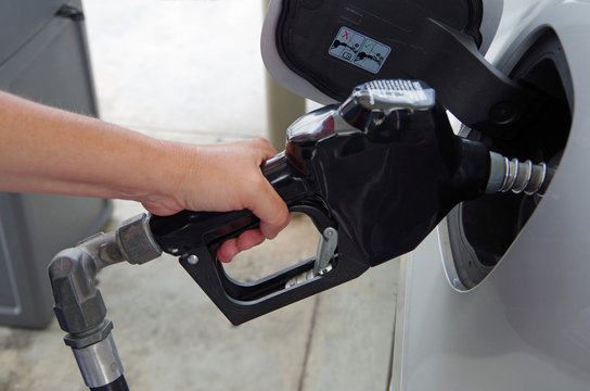 Hand Holding Gas Pump Inserted Into Gas Tank Of A Car