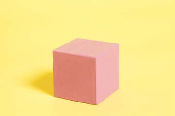Red wooden cube on yellow background