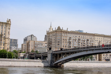 Fototapeta na wymiar Metal bridge across the river to the city, embankment with houses