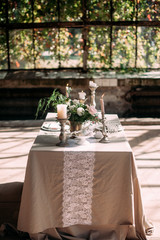 decorated table with flowers, candles and sweets in greenhouse