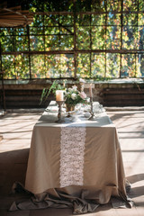 decorated table with flowers, candles and sweets in greenhouse