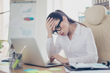 Strong headache. Tired sick business lady lawyer with strong migraine grimace. She is wearing the formalwear, sitting at the office, touching her forehead