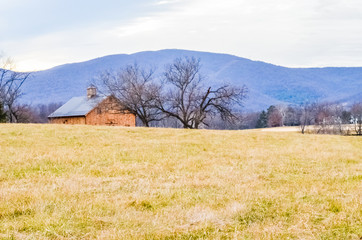 Rural countryside landscape in Virginia with farm or barn wooden house, mountains and hills in autumn or winter