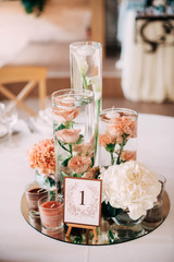 White and peach flovers in the water stand on mirror plate with gests frame