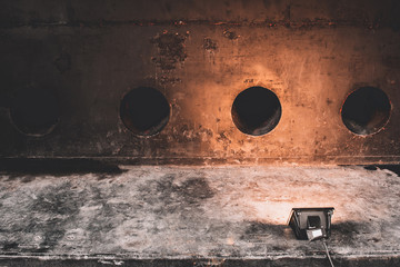 Studio spotlight with texture of rusted old painted metal wall and hold. Old metal steel iron rust texture on background and studio spotlight. Spotlight and metal surface texture.