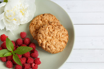 Delicious cookies with raspberries, mint and white peony flower on the plate.