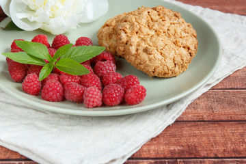 Delicious cookies with raspberries, mint and white peony flower on the plate.