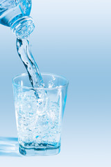 The bottle drinking water is being poured into the glass.