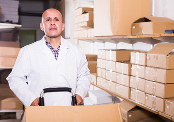 Worker performing loading works in storage © JackF
