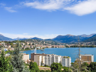 Obraz premium Aerial view of Lugano city with houses, lake and cityscape, and alpine Swiss mountains in Switzerland
