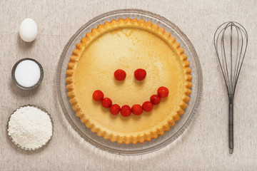 Fresh homemade biscuit cake with funny face from strawberries. Creative baked food concept. Top view.