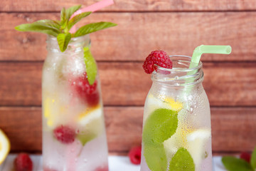 Cold cocktail with raspberries, lemon and mint. Wooden background
