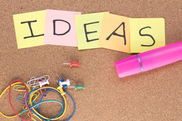 Ideas written on post it notes with a pink highlighter and rubber bands, taken on a wooden...