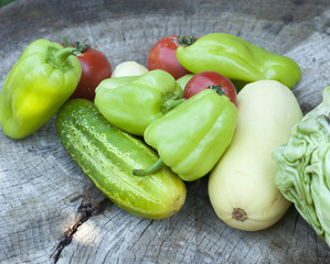 Group of green peppers, tomatoes, cucumber and pumpkins on wooden texture