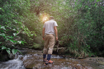 Man stretching on a waterfall in the rich green forest.