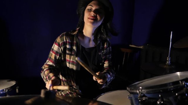Young Emotional Rock girl percussion drummer performing with drums, slow motion. Attractive young woman plays the drums