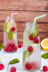 Cold cocktail with raspberries, lemon and mint. Wooden background