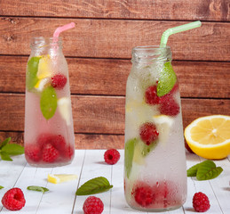 Cold cocktail with raspberries, lemon and mint. Wooden background