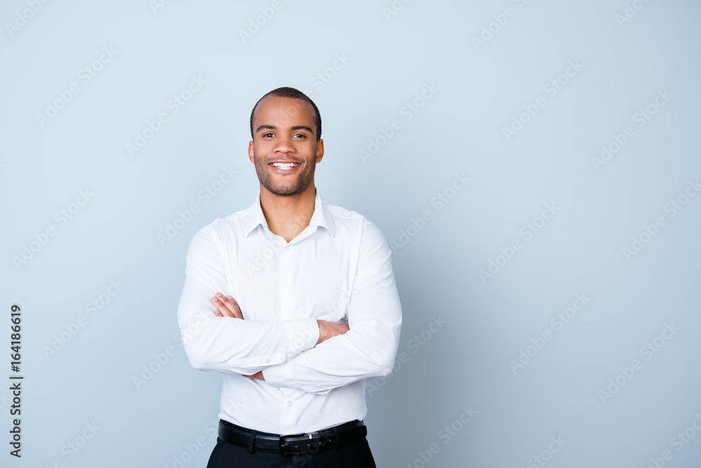 Wall mural Successful smiling young handsome american guy banker in formal outfit on pure background with crossed hands. So rich and confident, attractive and smart