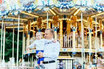 Father and son playing in amusement park at the evening time. Concept of friendly family