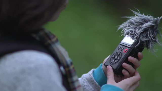 Woman with audio recorder in forest.