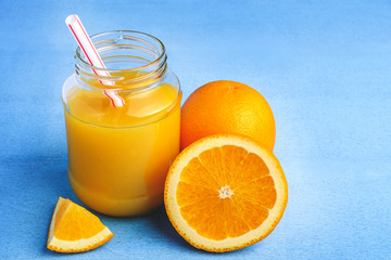 Fototapeta na wymiar Fresh orange juice in the glass next to the orange slices on blue wooden table