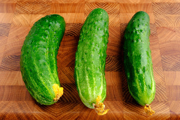 fresh green cucumbers on wooden cutting board close-up