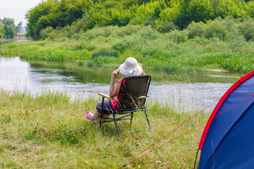 The woman on the Bank of the river sits .