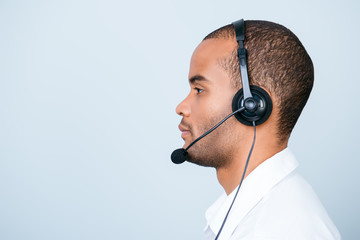 Side profile portrait of a handsome american guy call centre operator in a headset. He is isolated...