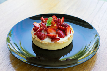 fresh strawberries on top Cheesecake in black plate on wooden board
