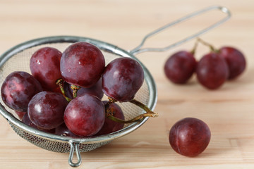 bunch of red grapes on a wooden table. 