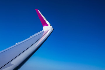 Naklejka premium Wing of plane on blue sky background