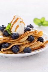Crepes served with fresh blueberries, ice cream and caramel sauce